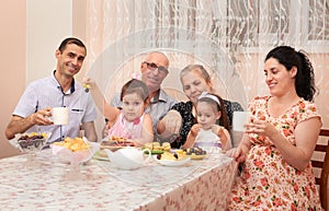 Big family drinking tea in dining room, pregnant woman