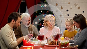 Big family eating Xmas dinner, chatting and smiling, having good time together