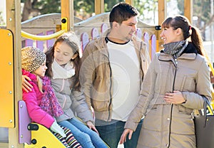 Big family of four resting at children slide