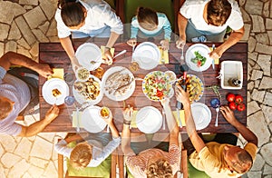 Big family have a dinner with fresh cooked meal on open garden t