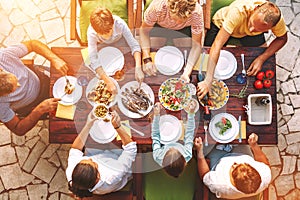 Big family have a dinner with fresh cooked meal on open garden terrace photo