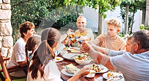 Big family have a dinner on garden terrace