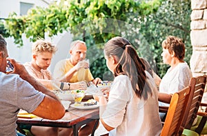 Big family have dinner on open garden terrace