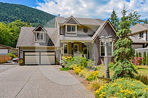 Big family house with concrete driveway, two garage doors, decorated front yard