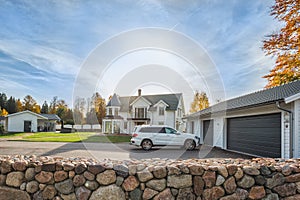 Big family house with double size garage and car parked in front. Residential house with concrete driveway and entrance door under