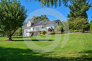 Big family house on a farm. Residential house with big green lawn in front on sunny day in British Columbia