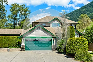 Big family house with wide concrete driveway and green wide garage door