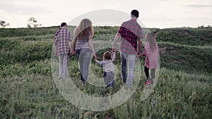 Big family mom dad girl and two sons are walking among the beautiful countryside and smiling happily. The concept of an
