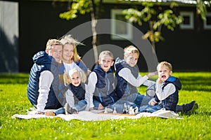 Big Family Relaxing In Green Nature. Happy family portrait on outdoor, group six people sit on grass, summer season