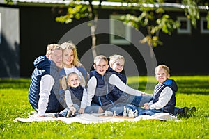 Big Family Relaxing In Green Nature. Happy family portrait on outdoor, group six people sit on grass, summer season