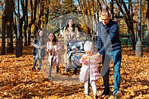 Big family spends time together in autumn city park, children and parents, happy people walk and relax, ride scooters, beautiful