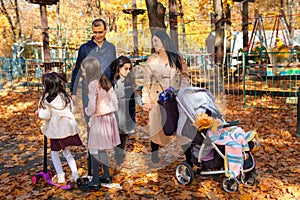 big family spends time together in autumn city park, children and parents playing, happy people walk and relax, ride scooters,