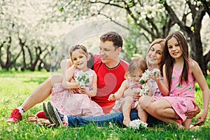 Big family with three little daughters spending time together in summer park