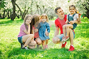 Big family with three little daughters spending time together in summer park, mother, father and sisters having fun photo