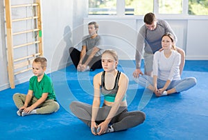 Big family before training martial arts performs stretching butterfly