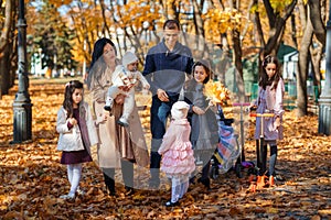 a big family walking together in an autumn city park, children and parents, happy people enjoying beautiful nature, a bright sunny