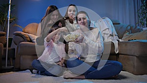 Big family watching late night TV show and eating popcorn at living room