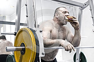 A big fat hungry man eats a hamburger with meat and cheese