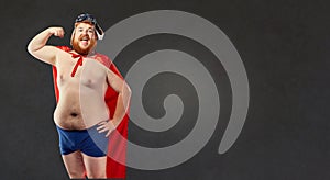 Big fat naked man in a superhero costume shows the muscles on hi