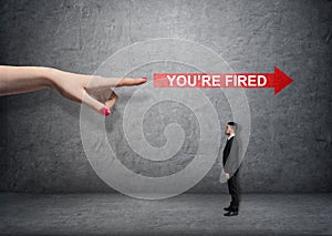 Big female arm pointing at red arrow with 'you're fired words' over small businessman