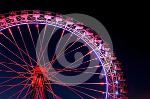 Big ferris wheel with festive red and purple illumination