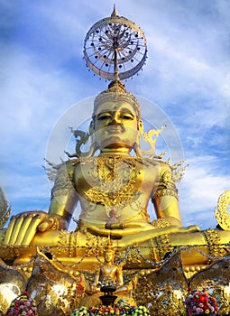 The Big Figurine of Gold Brass Phra Phut Sik Khi Thotsaphon (First Buddha) buddha sculpture statue sit among blue sky