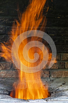 Big fire in a home tandoor at the cottage, closeup. Firewood is burned in a tandoor heating it before cooking meat