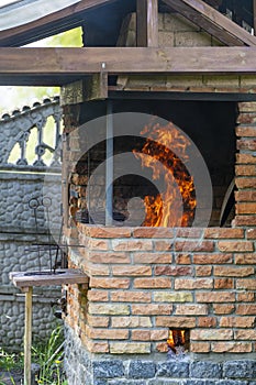 Big fire in a home tandoor at the cottage, closeup. Firewood is burned in a tandoor heating it before cooking meat