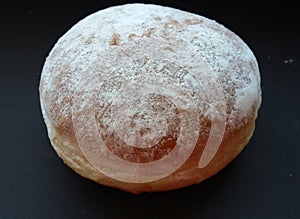 Big fluffy donut over black table. Sweet and tasty, just delicious!