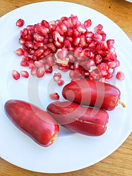 Big fresh red Dates and Pomegranates on the white plate. Closeup