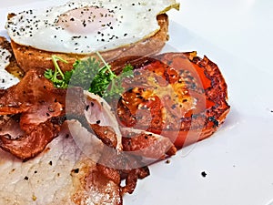Big fried grilled tomato of English breakfast with sunny fried eggs, bacon, tomatos, ham on Turkish flat grilled bread on white