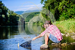 Big game fishing. relax on nature. hipster fishing with spoon-bait. fly fish hobby of man. Hipster in checkered shirt