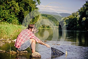 big game fishing. relax on nature. hipster fishing with spoon-bait. fly fish hobby of man. Hipster in checkered shirt