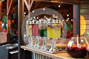 Big glass jars with tap filled with fresh cold drinks served in bar. Event with catering. Sangria cocktail.