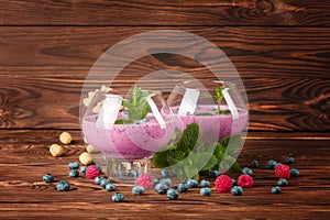Big glasses with cocktails on a wooden background. Appetizing milkshake with blueberries, mint and peanuts. Copy space.