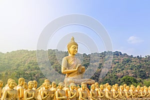 Big golden buddha statue and many small golden buddha statues sitting in thai temple