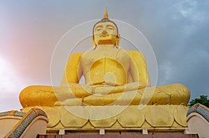 The big golden Buddha statue of Phu Salao temple with Mekong River flows through the Pakse city in beautiful sunset moment at Paks