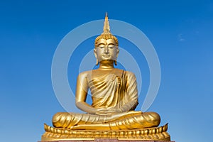 Big golden buddha statue sitting on blue sky background