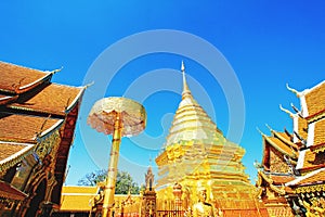 Big golden pagoda, umbrella and buddha statue with clear blue sky backgound at wat Phra That Doi Suthep Chiangmai, Thailand.