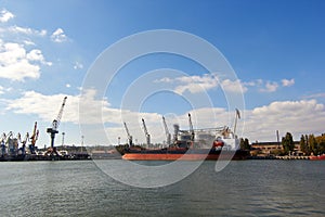 Big grain terminal at seaport. Cereals bulk transshipment from road transport to vessel. Loading grain crops on ship