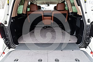 The big gray empty trunk of SUV car with fabric mat and with leather folder on the floor Open luggage carrier of car closeup