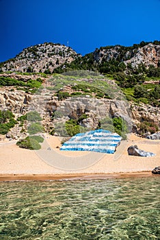 Big greek flag painted on large rock at Tsambika beach at Rhodes island in Greece