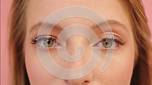 Big green eyes of young caucasian smiling woman, close up, studio shot