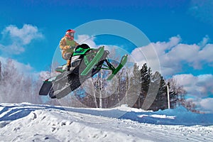 Big green Sport snowmobile jump. Cloud of snow dust from under snowmobile tracks. photo
