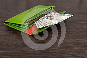 Big green wallet with money on a brown background. The wallet in which the dollars lie. Concept of saving money. a stack
