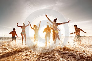 Big group of friends at sunset sea beach