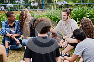 We are a big group today. a group of young students studying together while being seated in a park outside during the