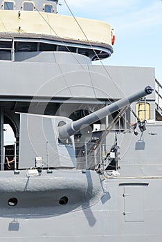 Big gun cannon on right side of warship. Safety boat on a ship