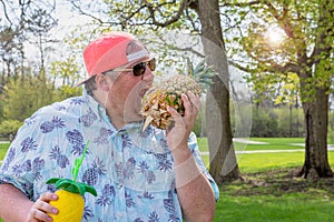 Big guy pretending to take a big bite of a pineapple