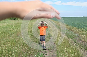 Big hand shelter little tiny boy in field